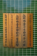 Vertical wooden plaques with Korean text mounted against a tiled green wall.