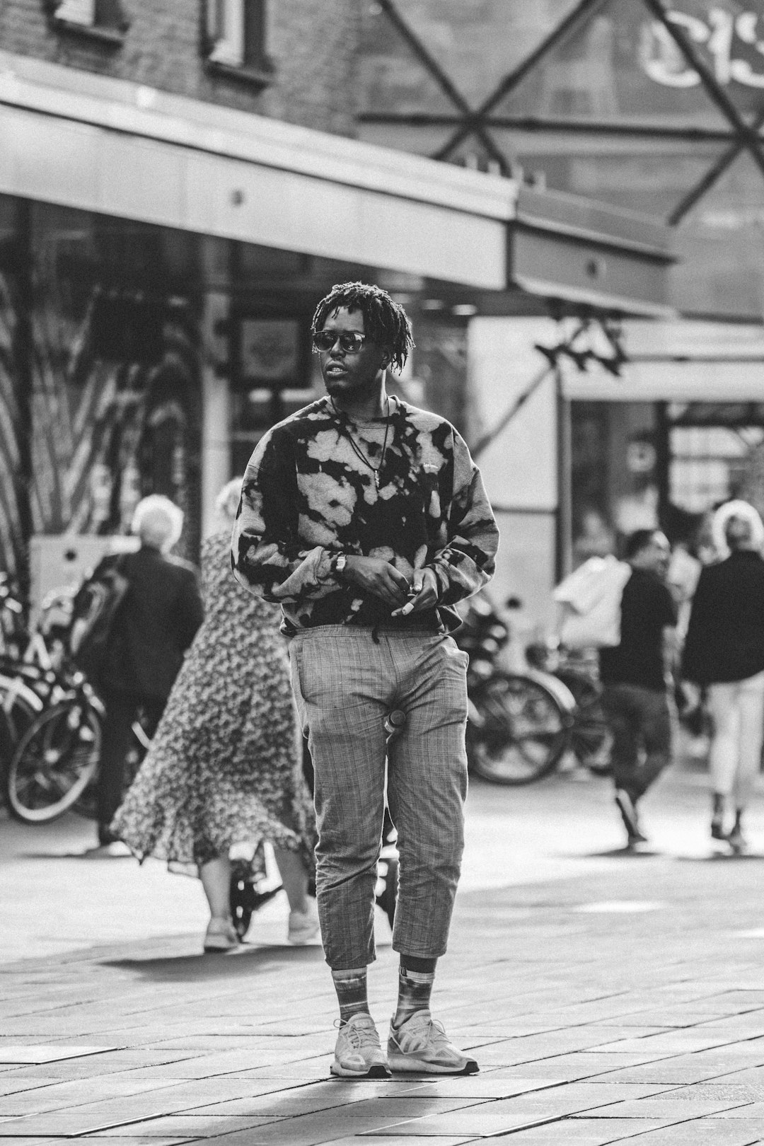 grayscale photo of woman in jacket and pants walking on street