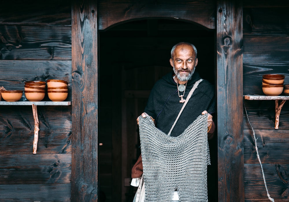 man in black and white checkered dress shirt standing beside brown wooden door