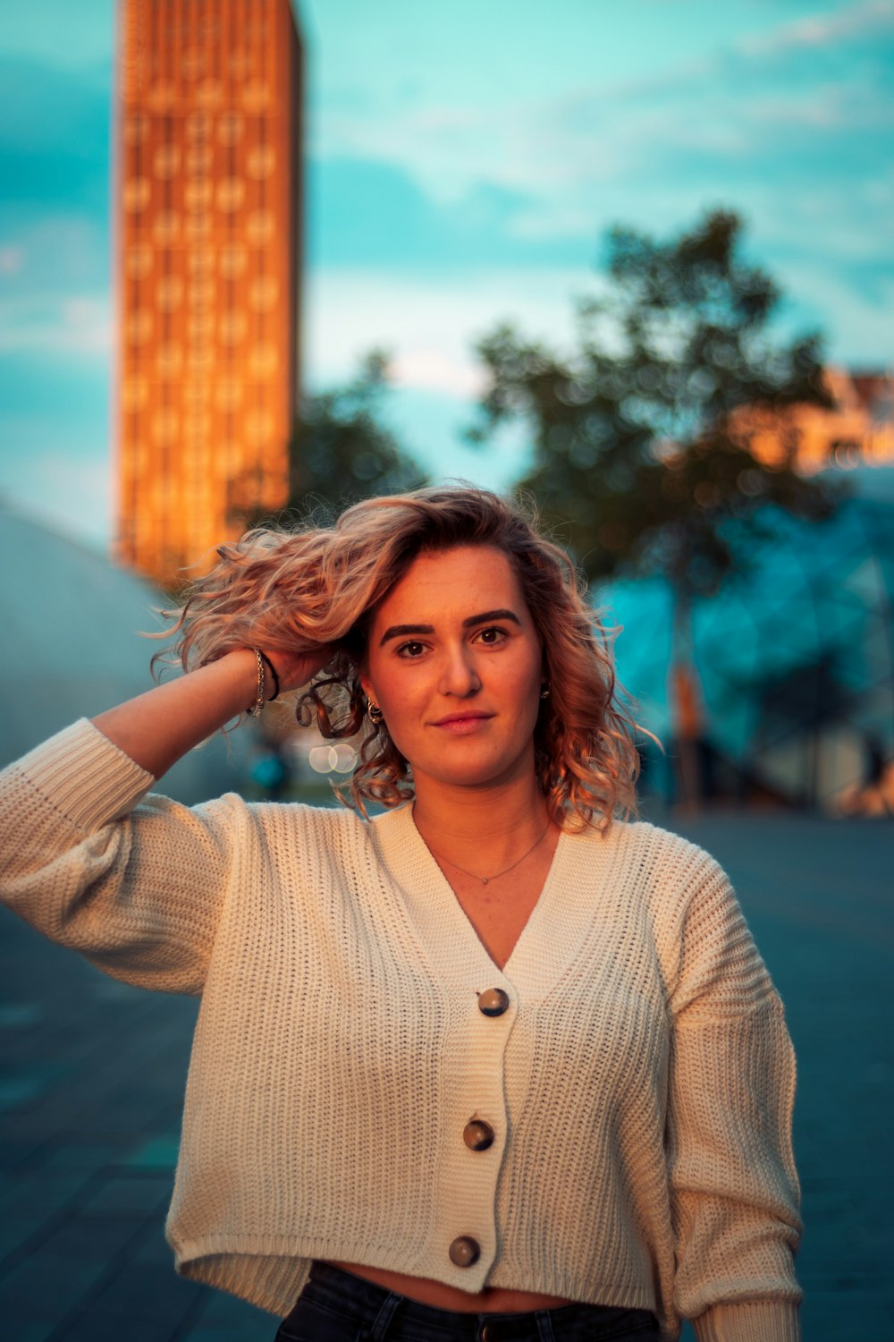 woman in beige button up cardigan standing near body of water during daytime