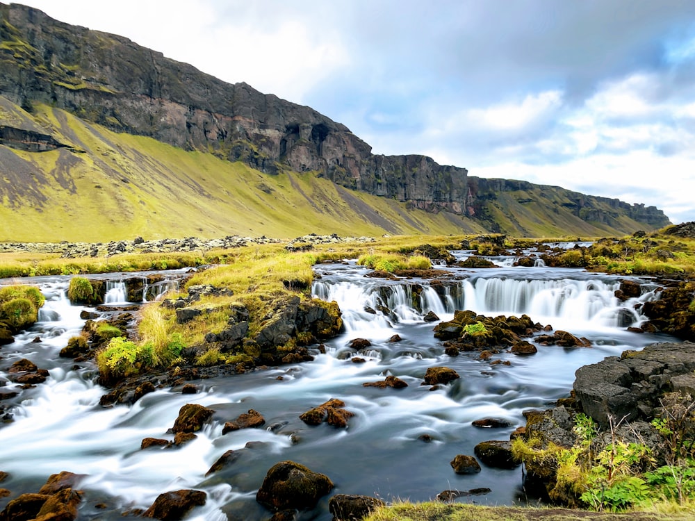 green and brown mountain beside river during daytime