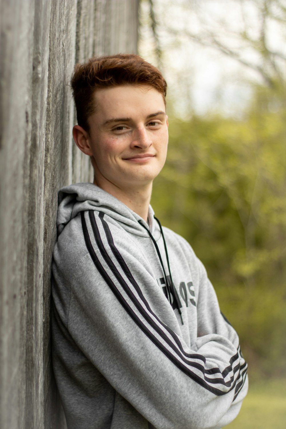 man in grey hoodie standing beside grey concrete wall during daytime