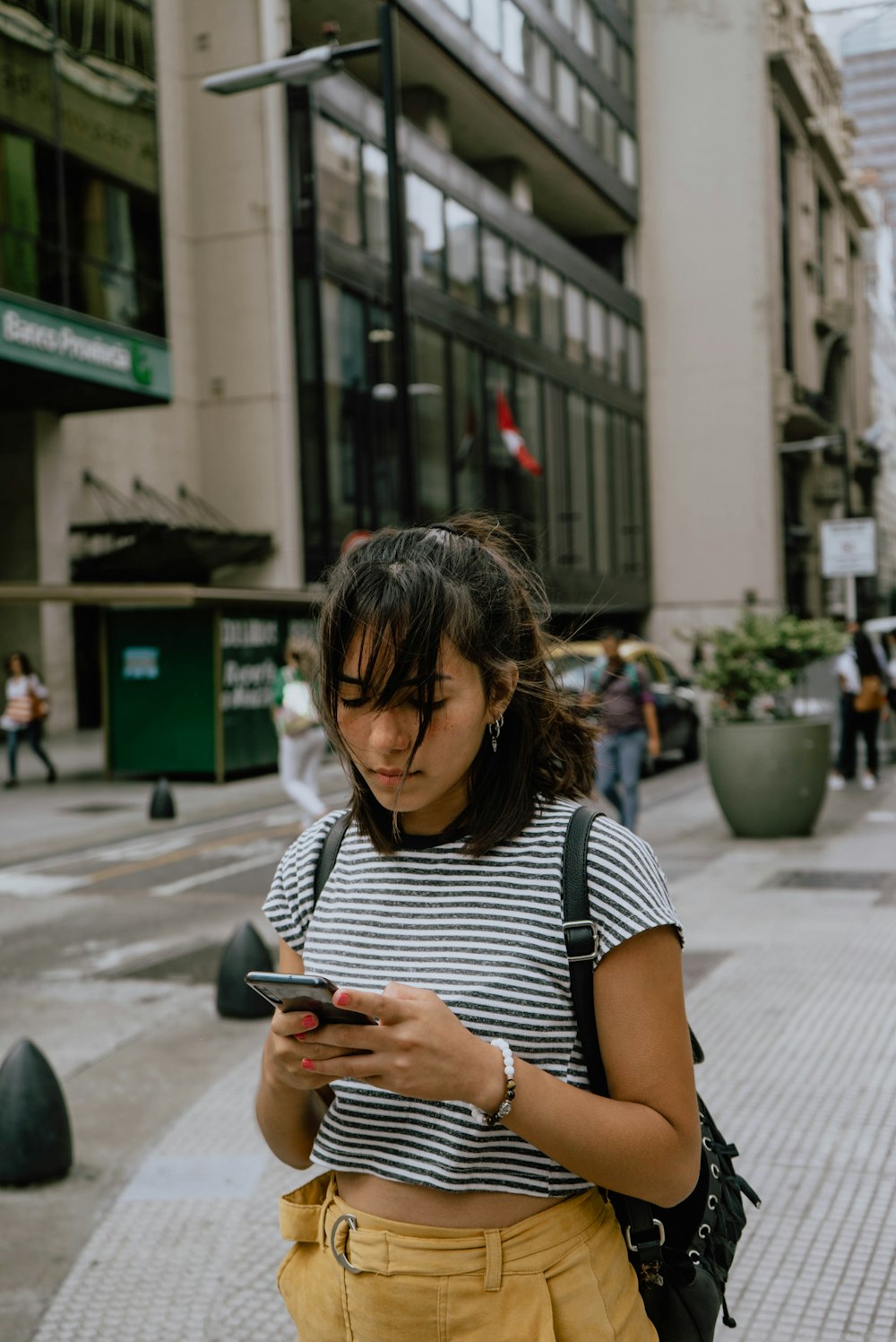 woman in black and white stripe shirt using smartphone