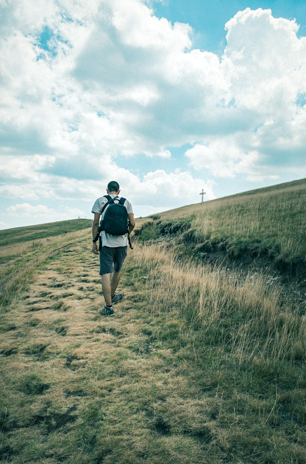 man in black jacket walking on brown field during daytime