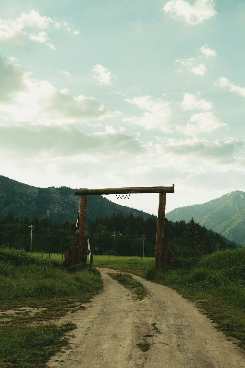 brown wooden post near green grass field and mountain during daytime