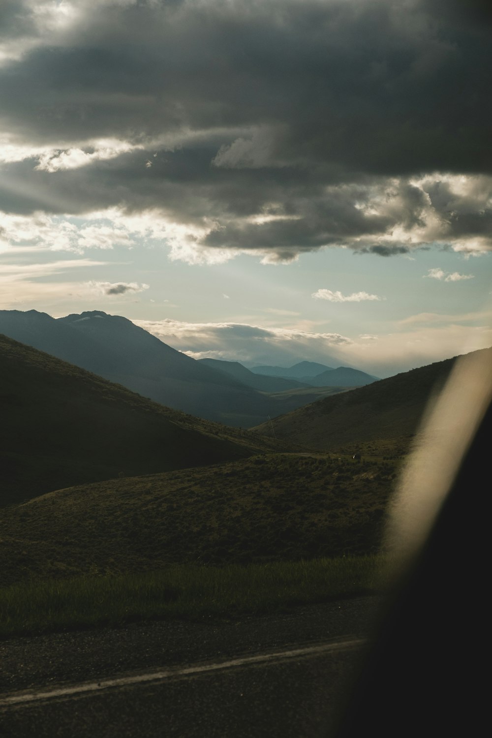 green grass field and mountains under white clouds