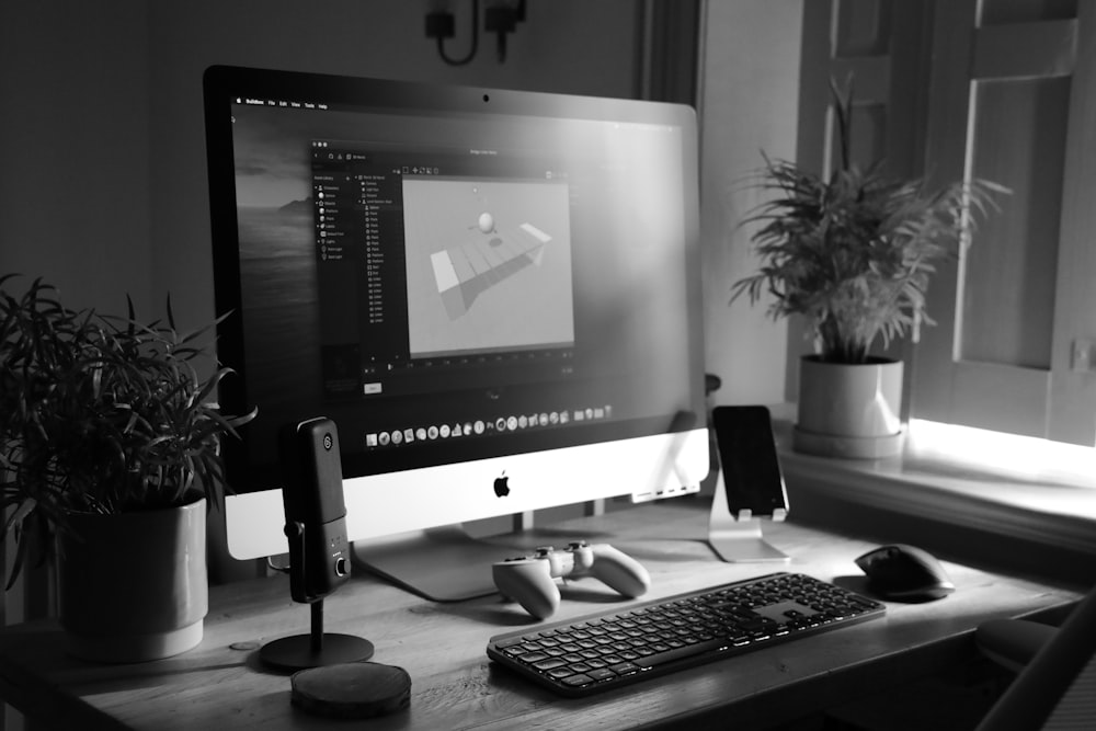 silver imac with black computer keyboard and black and silver speaker