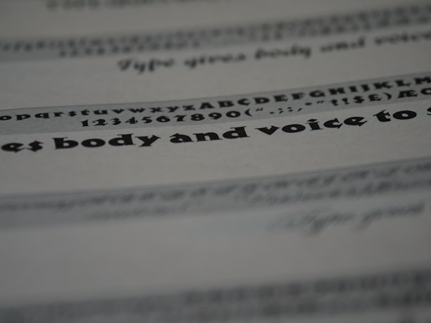 An image featuring a close-up view of text on a paper. The text includes various font styles and sizes, focusing on a bold and larger typeface in the middle. The image is blurred in certain areas, creating a depth of field effect.