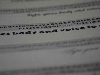 An image featuring a close-up view of text on a paper. The text includes various font styles and sizes, focusing on a bold and larger typeface in the middle. The image is blurred in certain areas, creating a depth of field effect.
