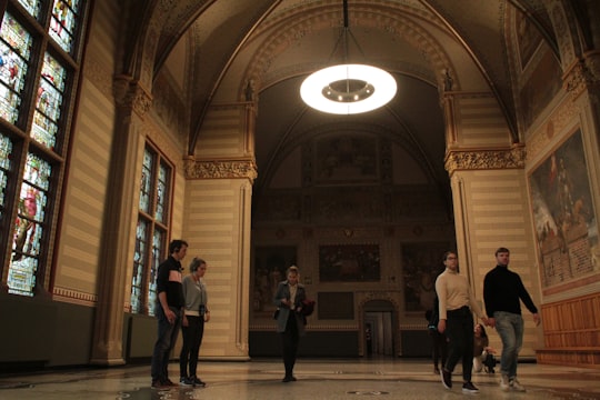 people walking on hallway inside building in Rijksmuseum Netherlands