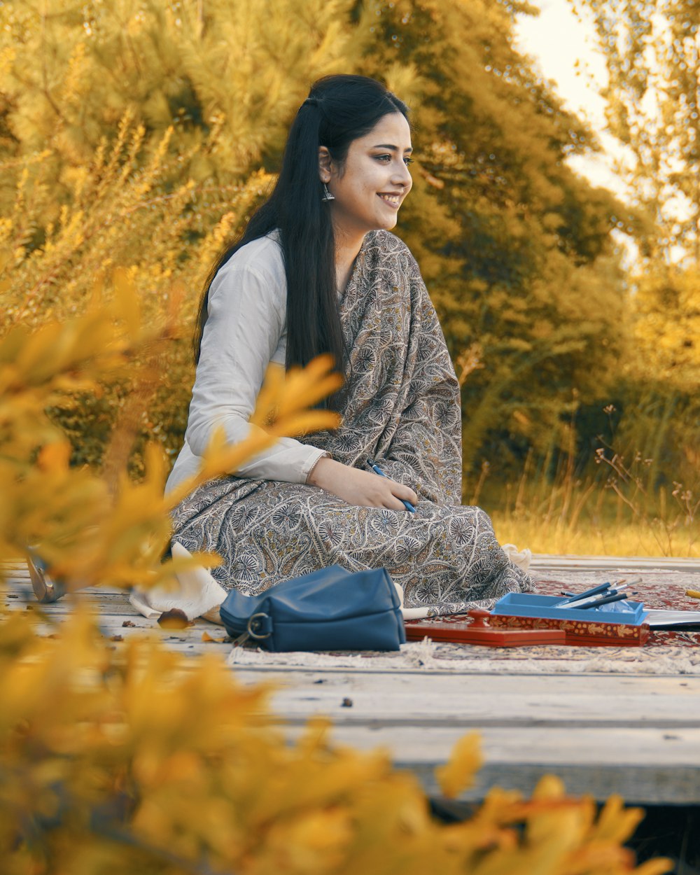 woman in white long sleeve shirt sitting on red textile on ground during daytime