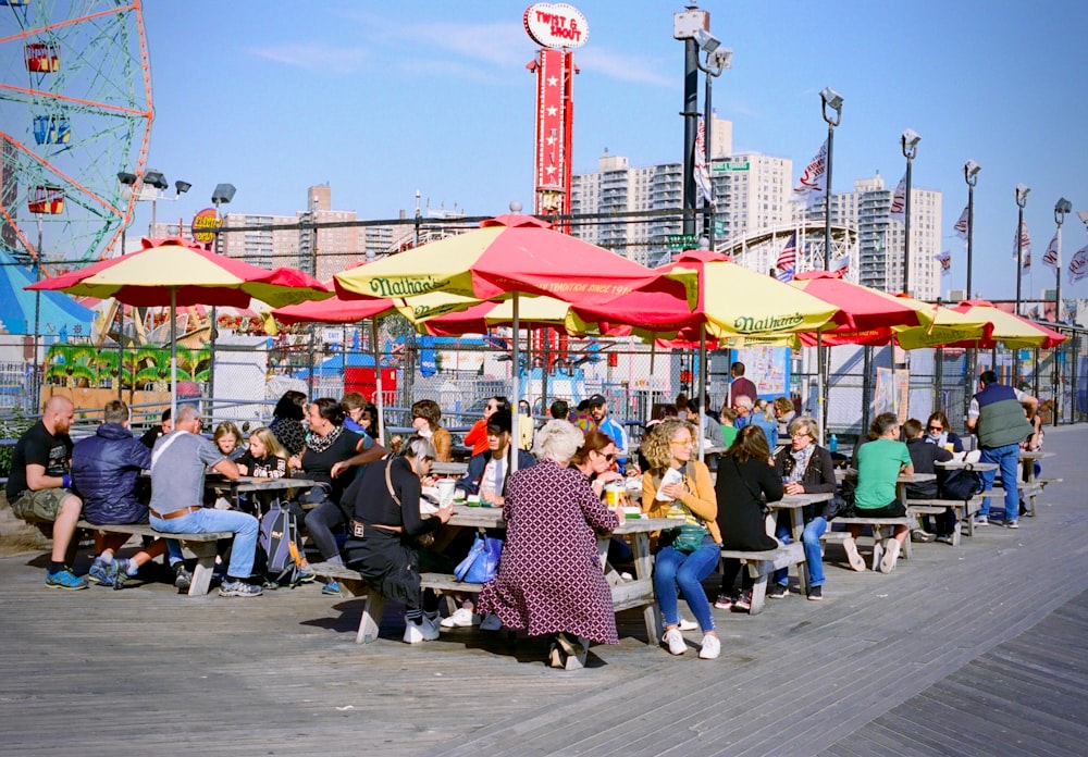 people sitting on bench near red and white street post during daytime