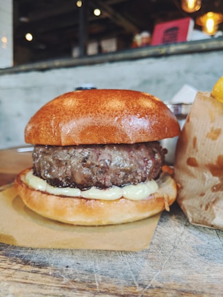 A juicy cheeseburger with melted cheese, crispy lettuce, and a toasted bun on a rustic wooden table.