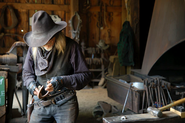 Artisan carefully crafting a leather sandal with traditional tools in a warm workshop.
