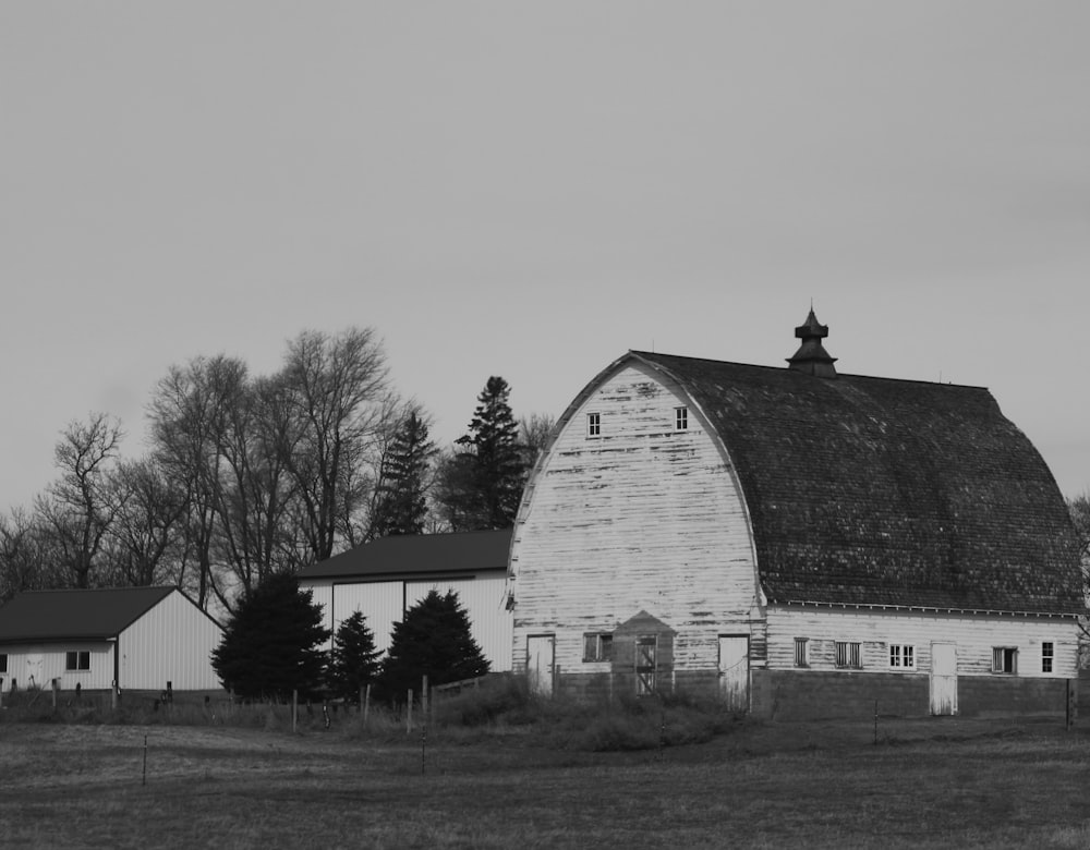 grayscale photo of a barn in the middle of a field