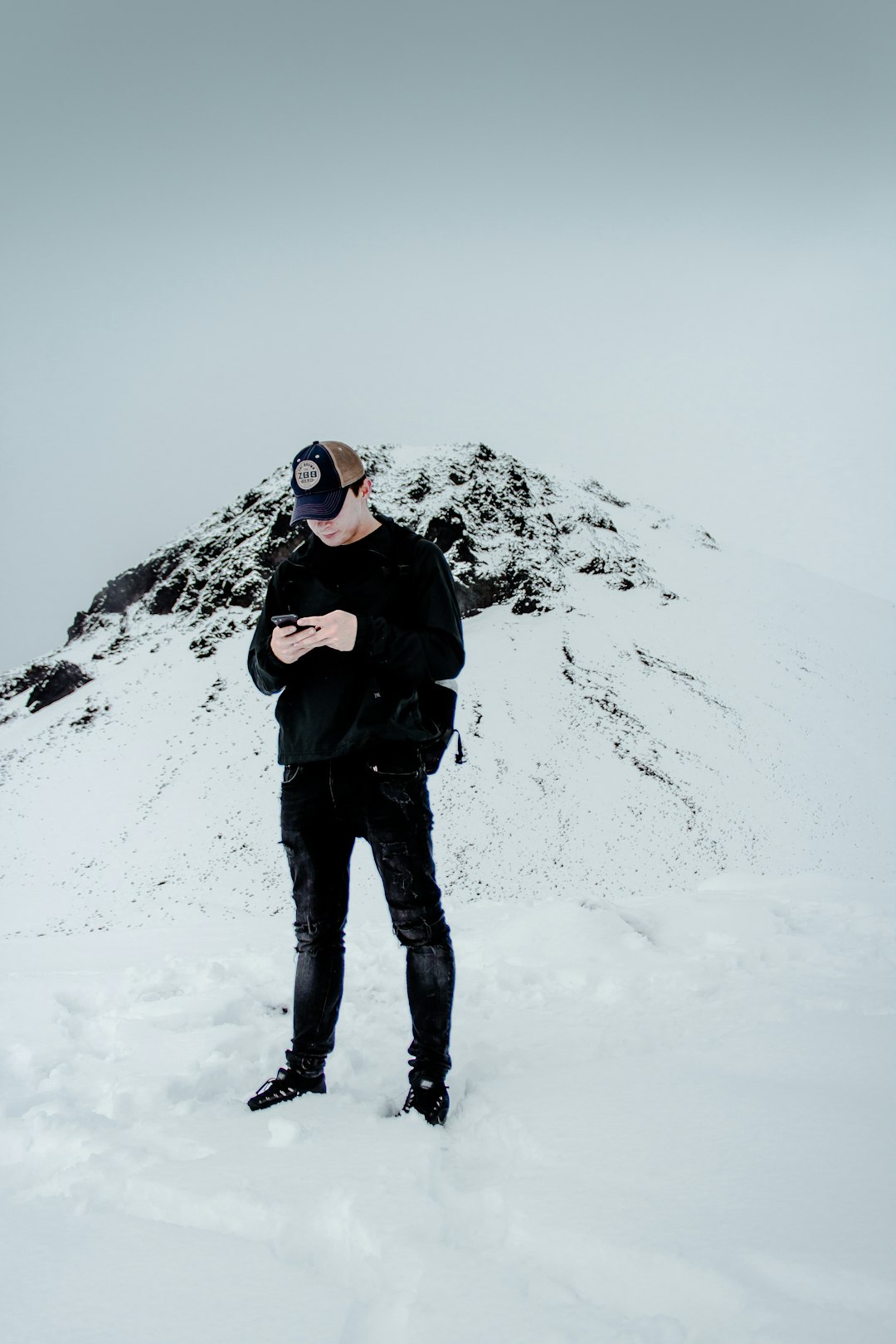 man in black jacket and black pants standing on snow covered ground