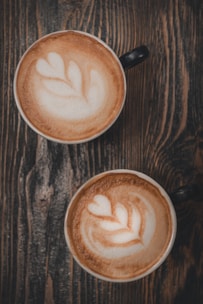 two cups of cappuccino on a wooden table