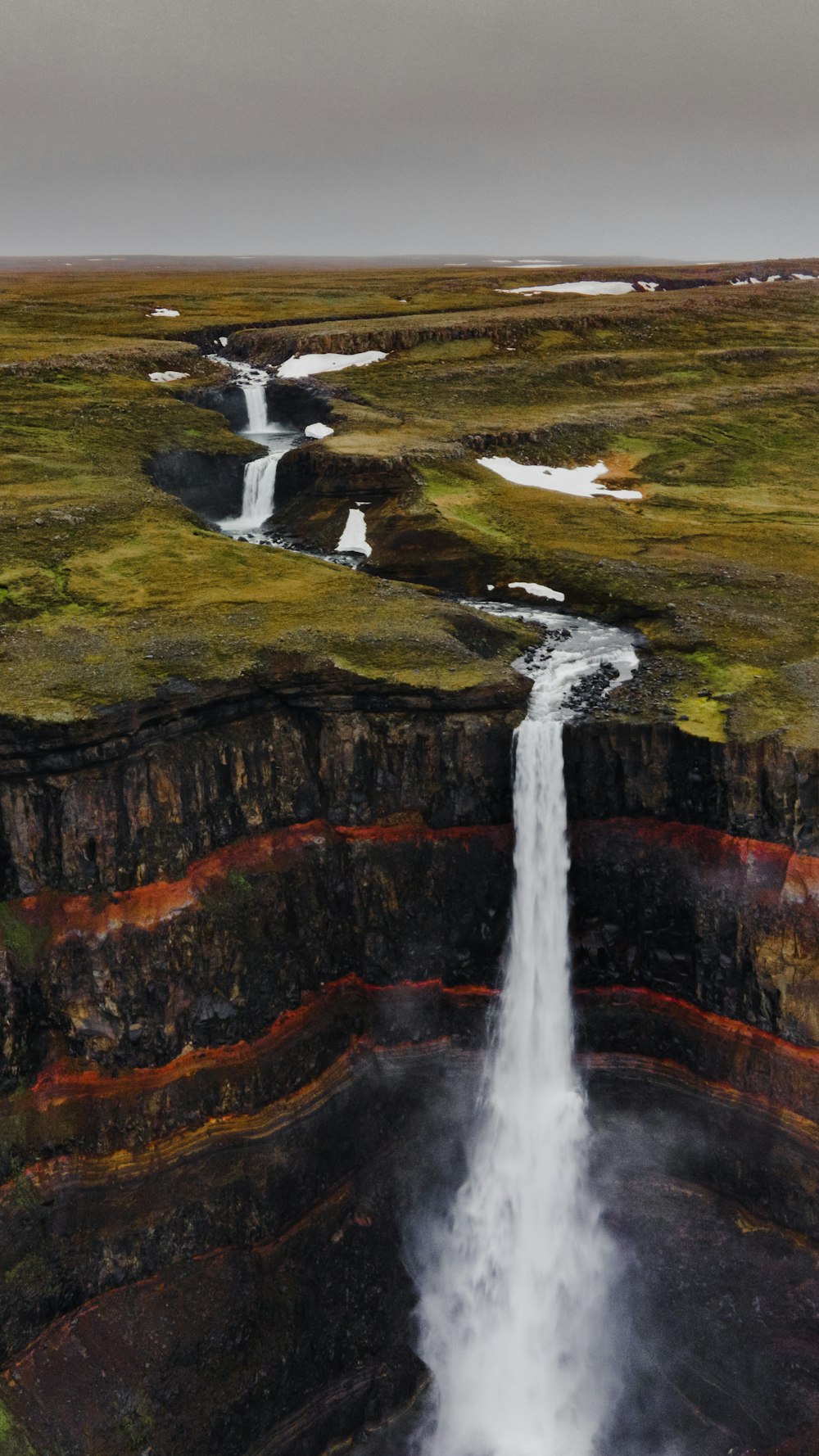 waterfalls on brown and green mountain during daytime