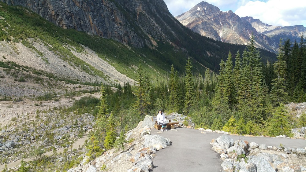 person in white shirt sitting on rock near river during daytime