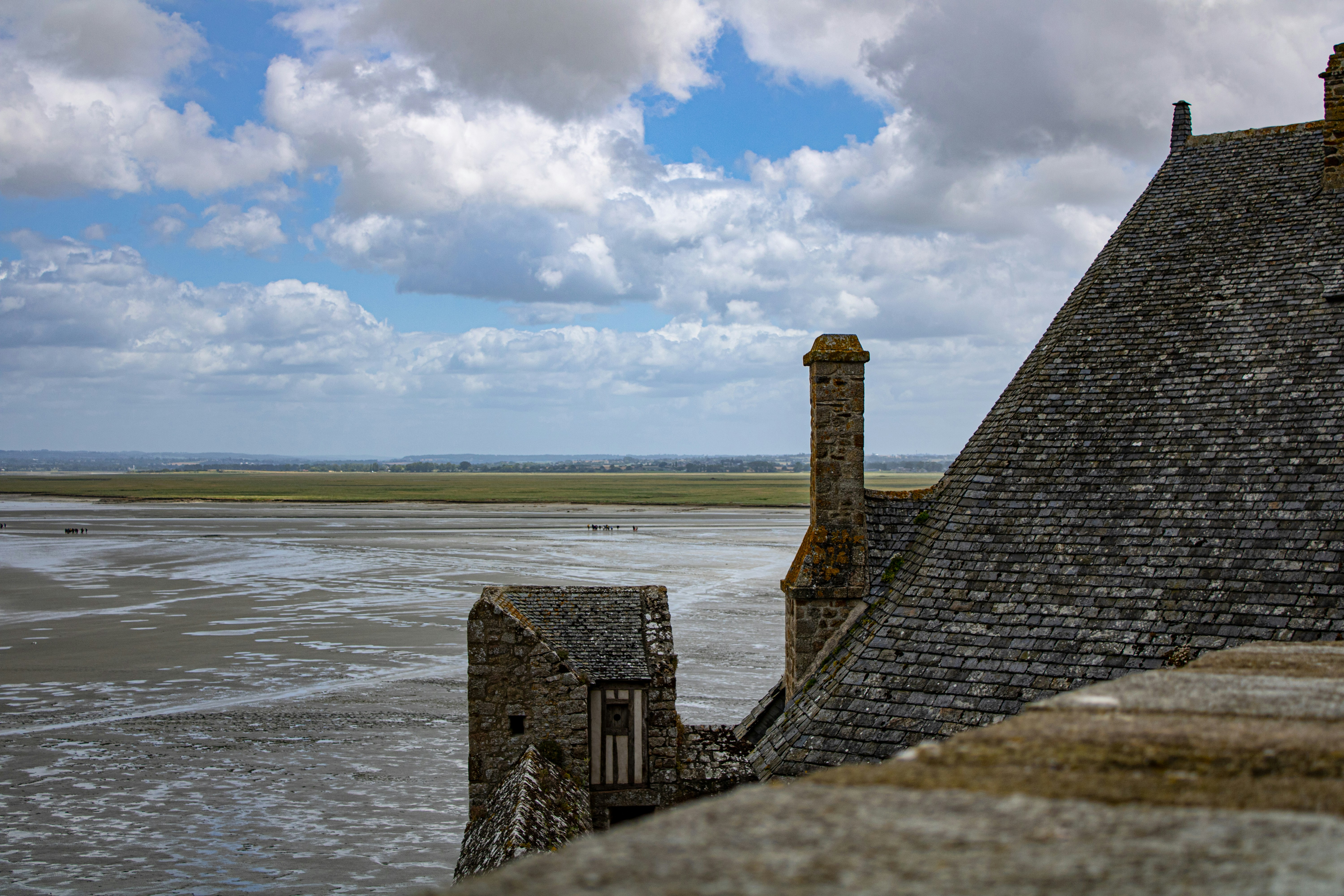bâtiment en briques brunes près de la mer sous le ciel bleu et les nuages blancs pendant la journée