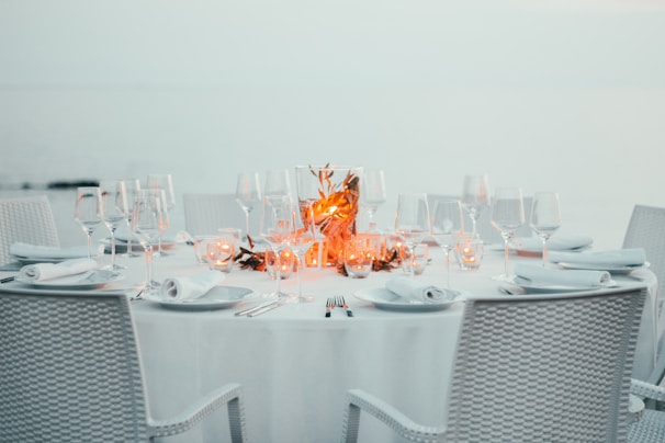 Elegant table setting in a villa overlooking the Aegean Sea at sunset, with soft candlelight.