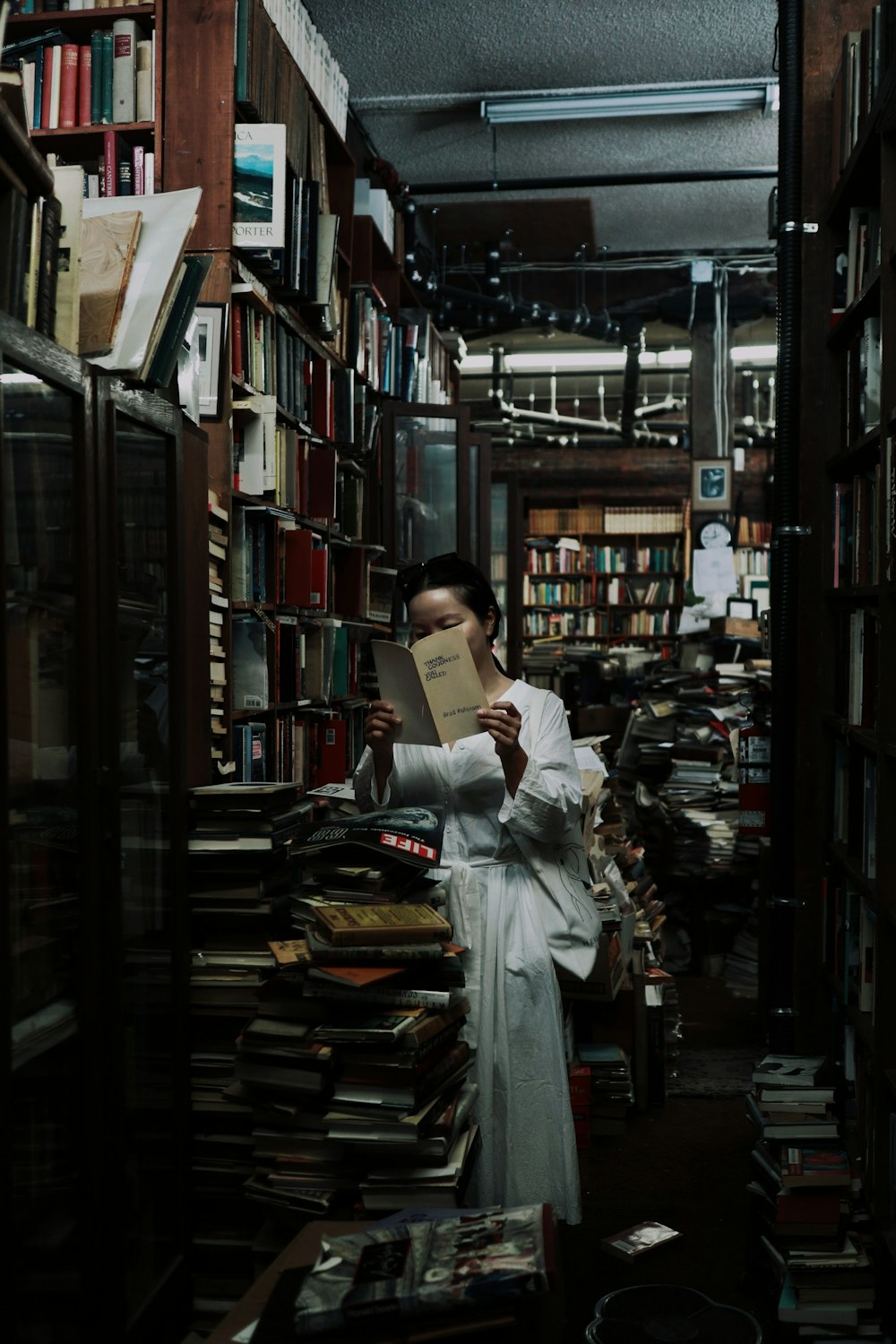 woman in white long sleeve shirt reading book in library