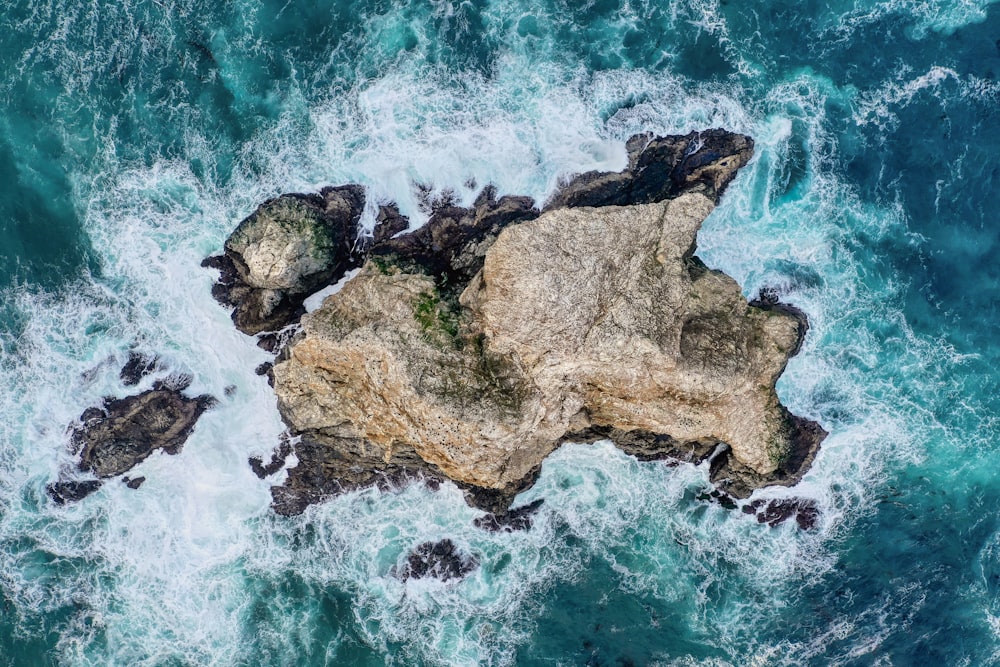 brown rock formation on body of water during daytime