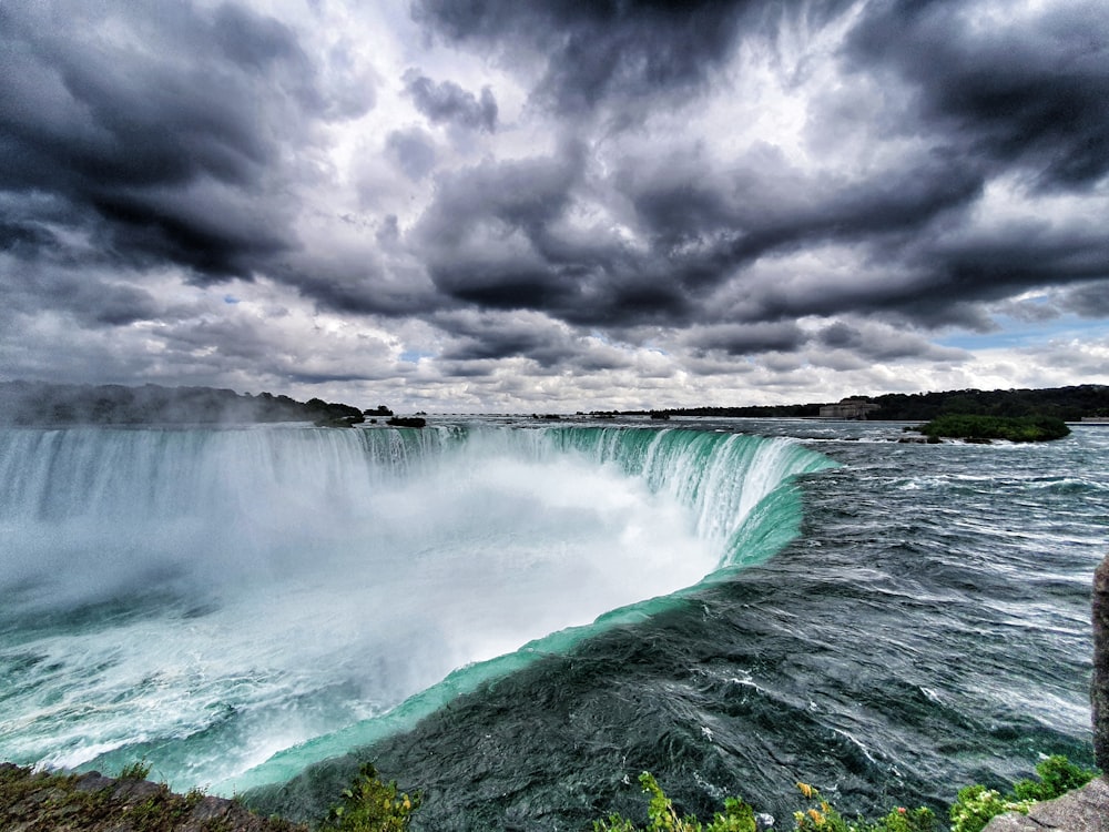 ocean waves crashing on rocks under gray clouds