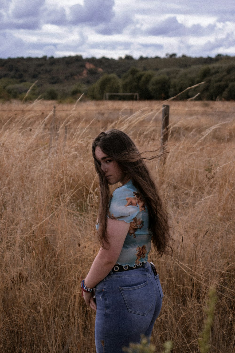 woman in blue denim shorts standing on brown grass field during daytime