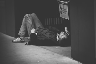 man lying on floor in grayscale photography