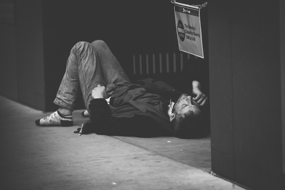 man lying on floor in grayscale photography