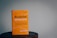 A book with a bright orange cover resting on a wooden surface. The title 'Beautiful Resistance' is prominently displayed in bold, stylized font, and the author's name, Jon Tyson, is indicated. The background is plain with a subtle, muted tone.
