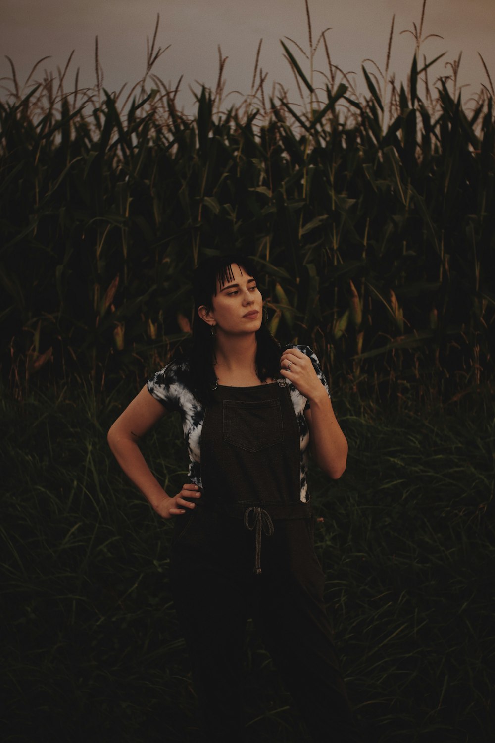 woman in black dress standing in the middle of corn field