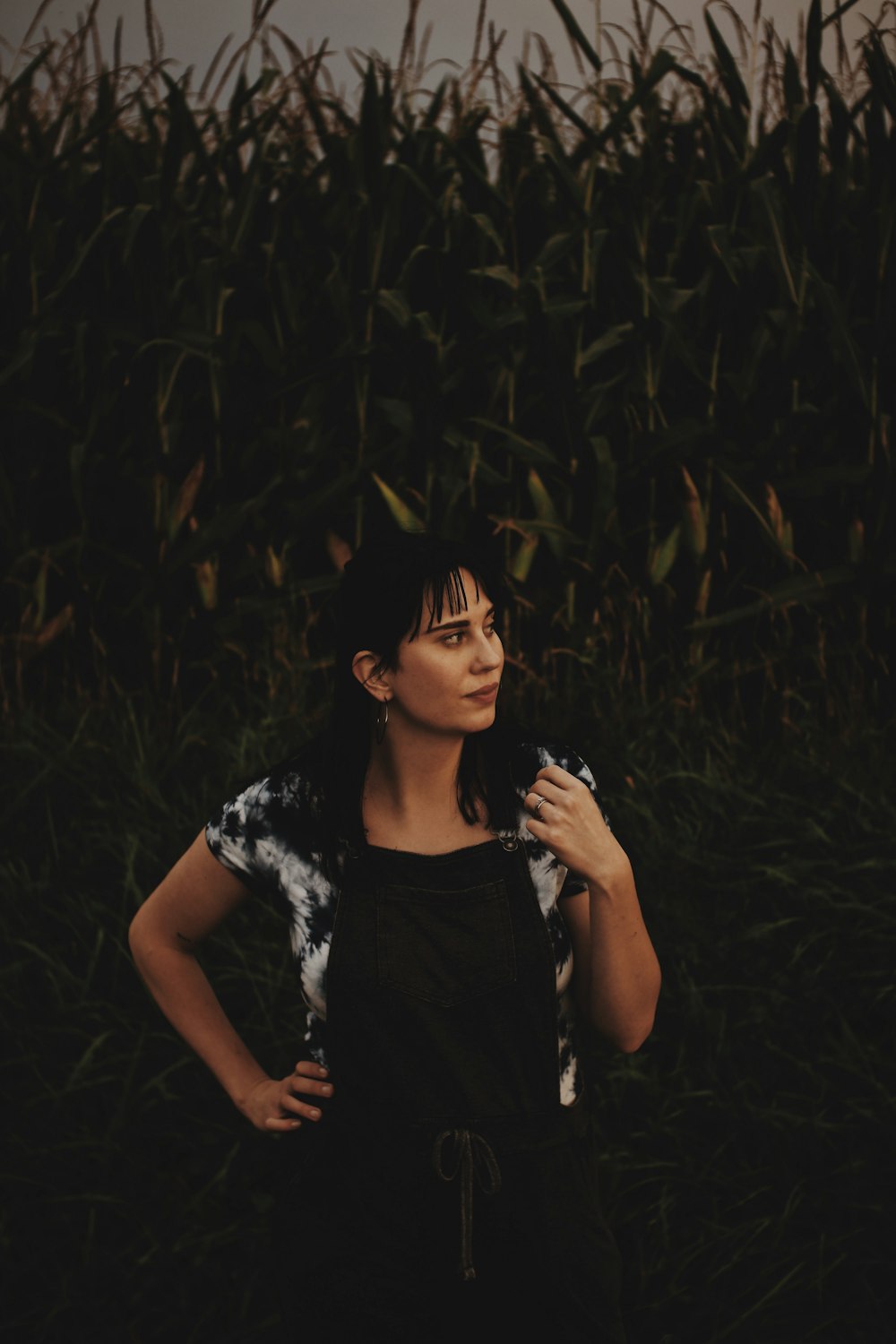 woman in black and white floral dress standing in the middle of the woods