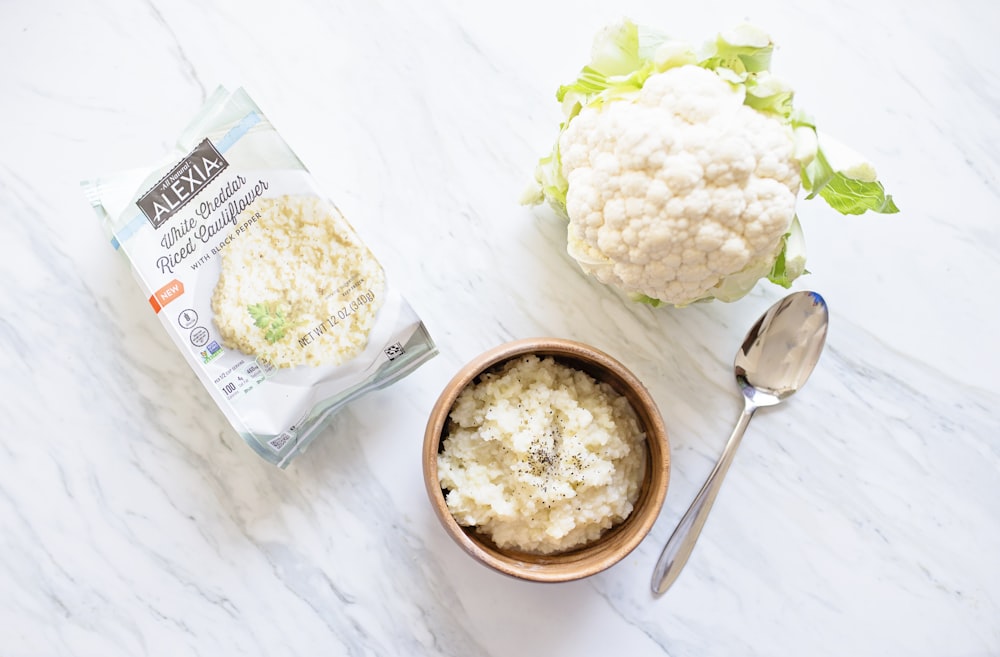 broccoli and cauliflower in brown bowl beside silver spoon