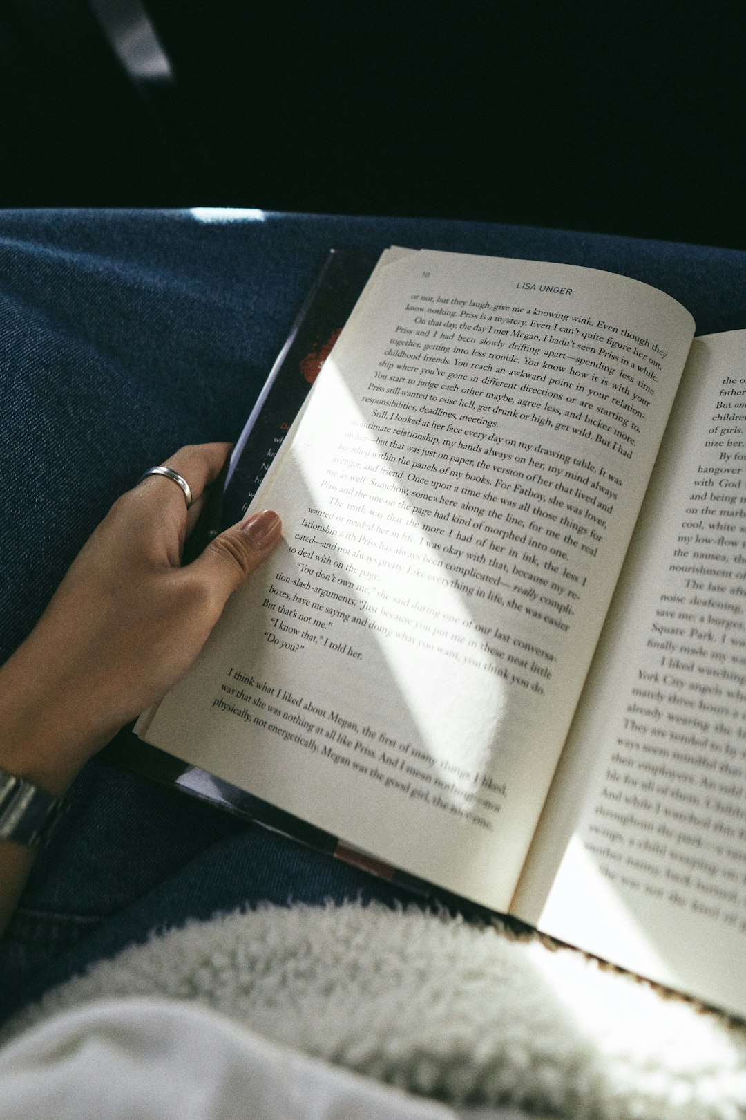 person holding book on blue textile