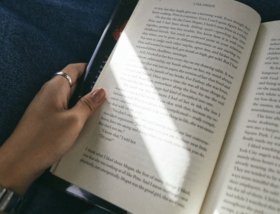 person holding book on blue textile