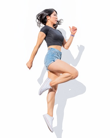 Dynamic shot of a woman jumping with energy, dressed in a sophisticated black and white fitness ensemble.