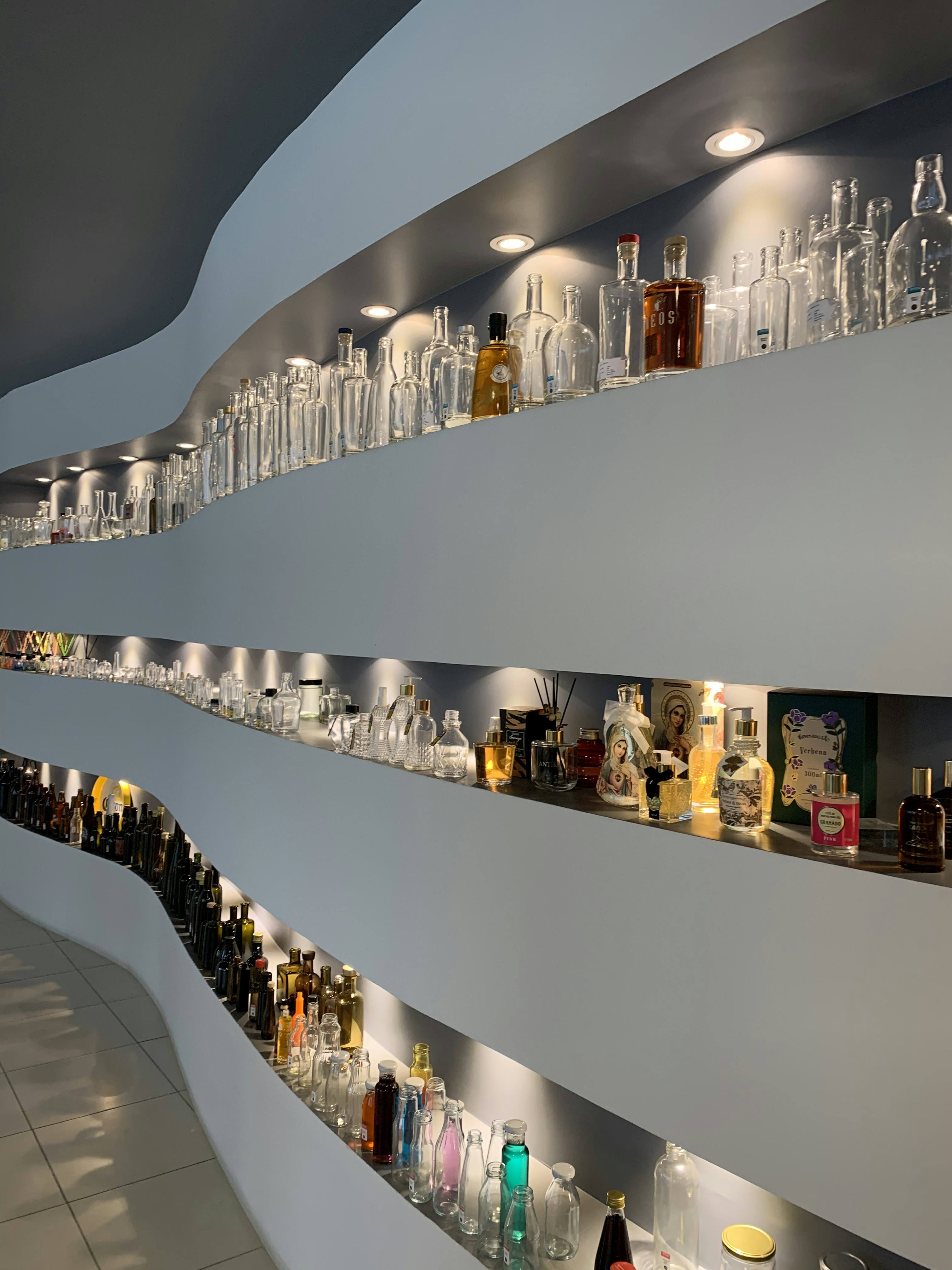 Rows of branded product bottles on a white retail shelf, bright studio lighting, clean white background, professional product photography