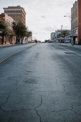 gray concrete road with cars parked on side during daytime