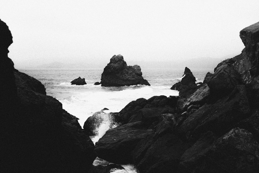 grayscale photo of rocky mountain beside sea