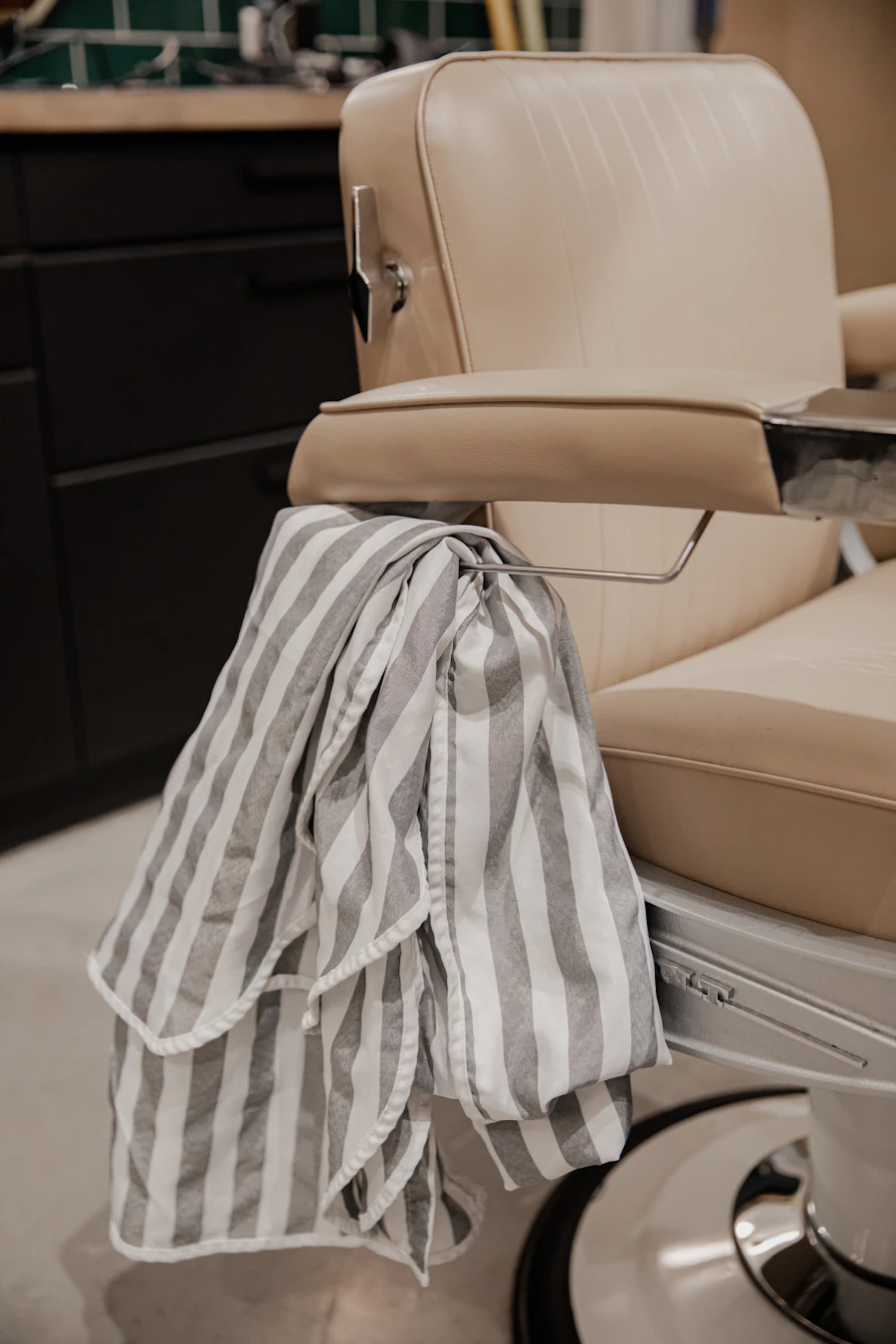 Cream vintage barber chair with a striped towel draped over it