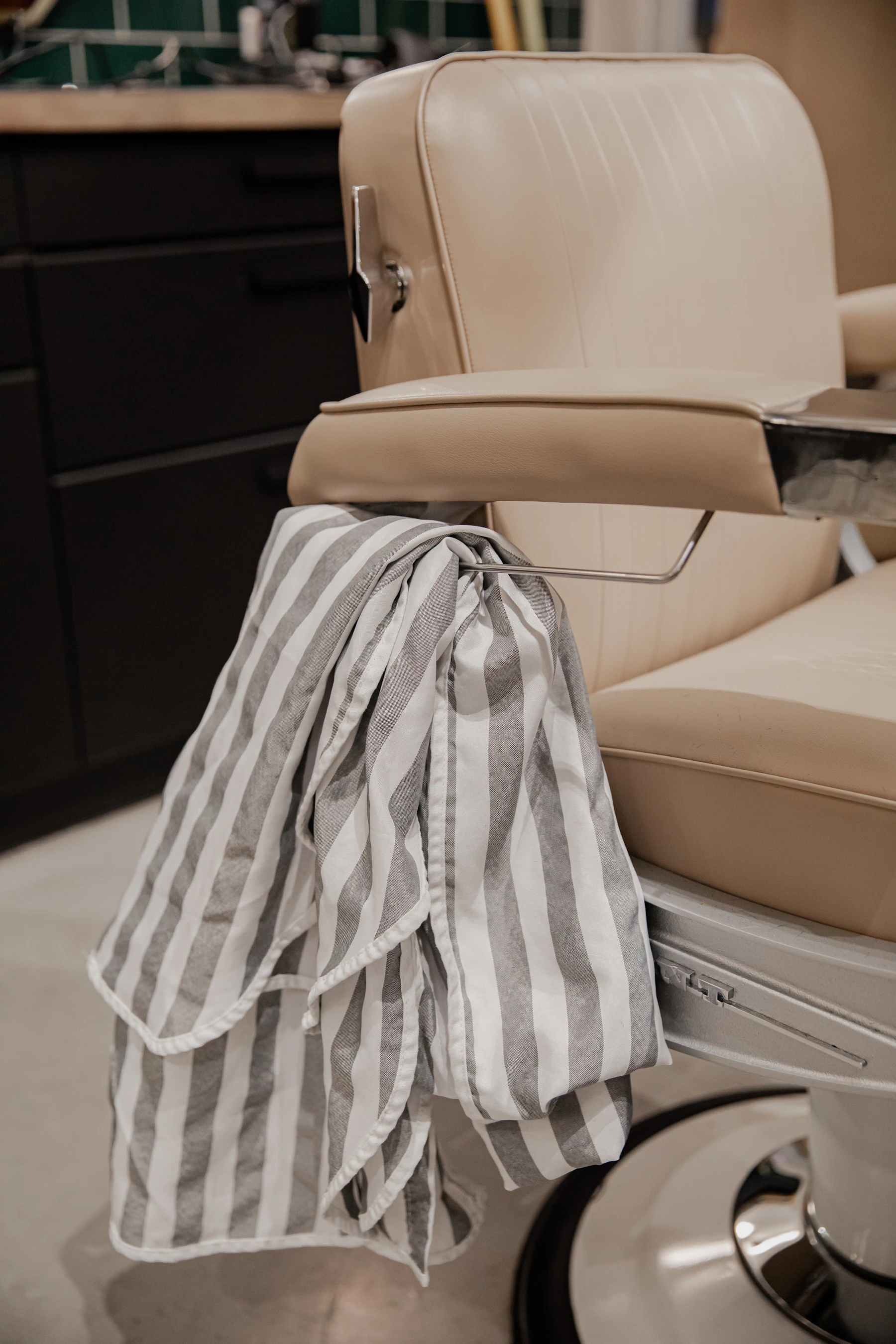 A grey striped barber's cloth draped over a chair