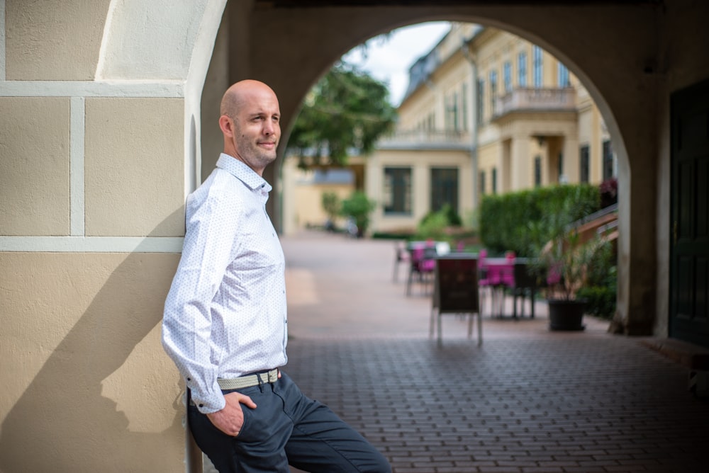 man in white dress shirt and black pants sitting on brown wooden bench during daytime