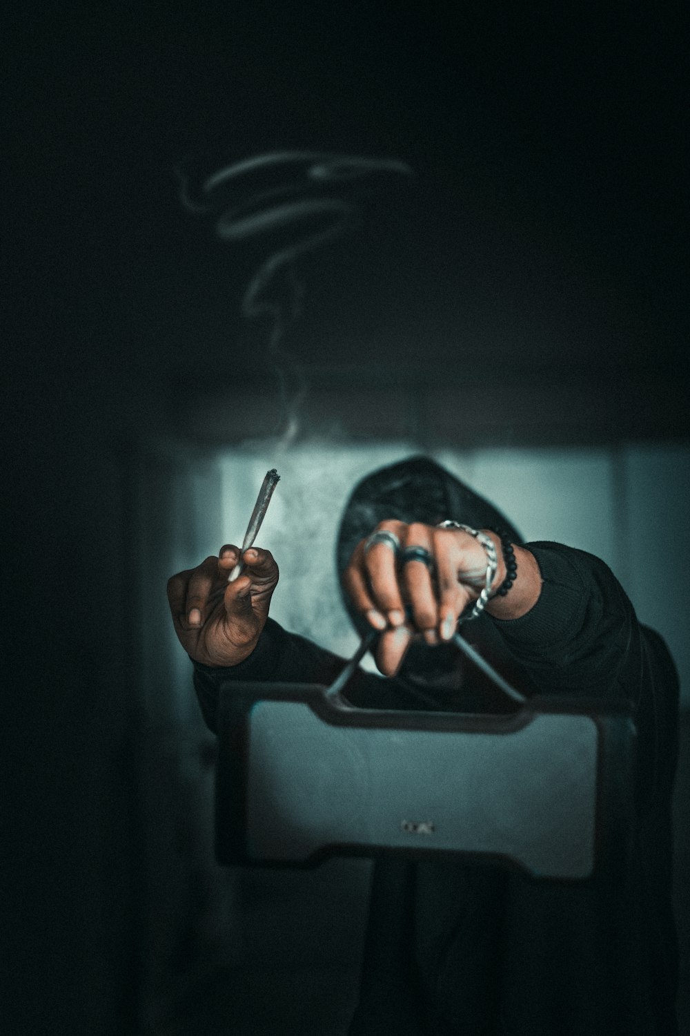hombre en camisa negra de manga larga fumando cigarrillo