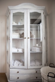 A linen cabinet with open shelves neatly stacked with folded towels and baskets.