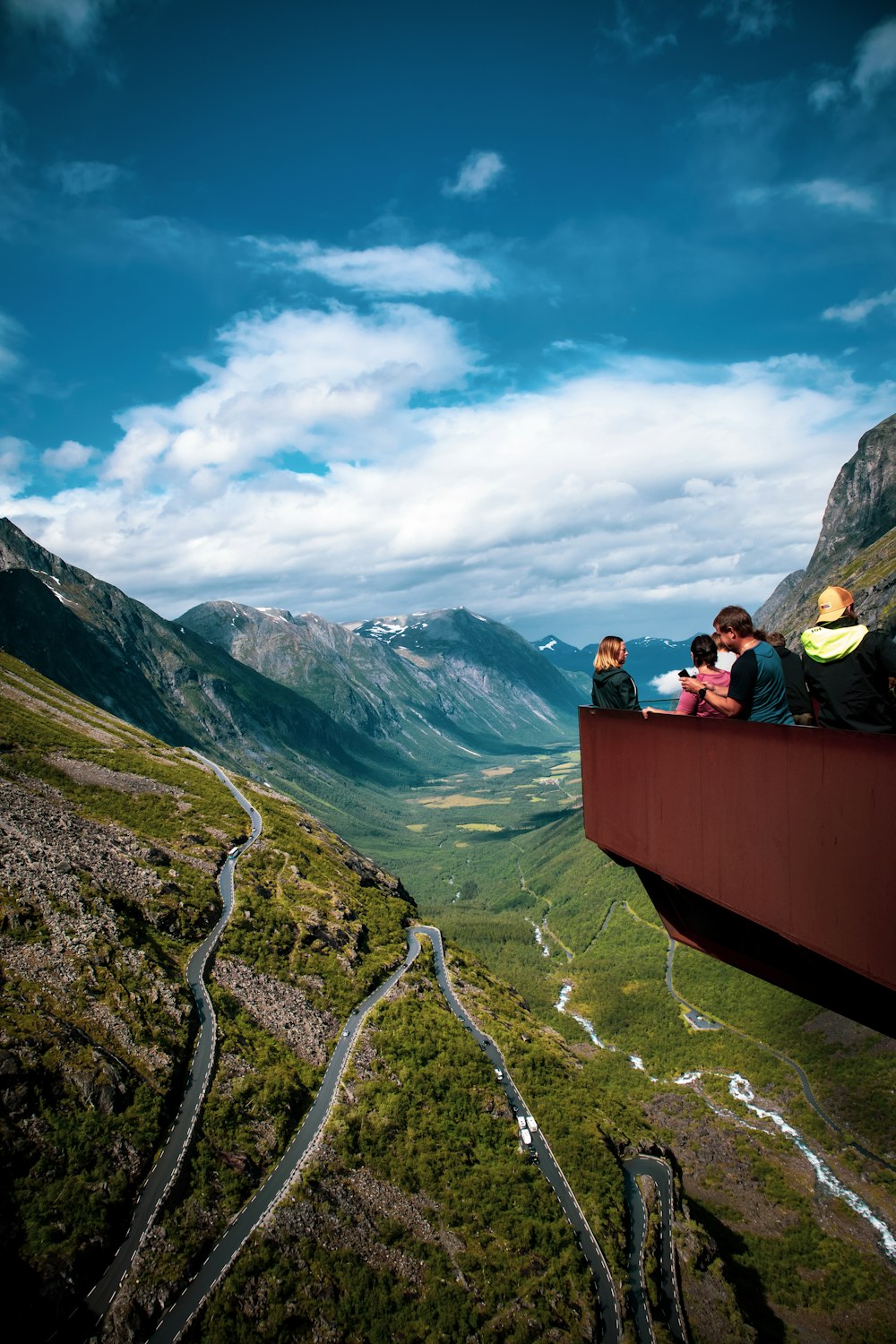 Persone che si siedono su una panchina di legno marrone sulla montagna durante il giorno