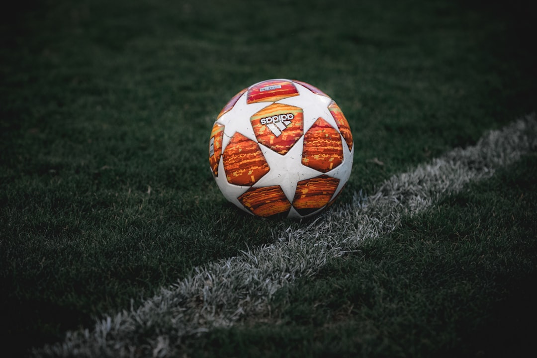 white and orange soccer ball on green grass field