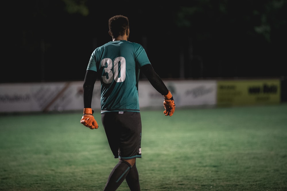 Mann im blau-weißen Nike-Fußballtrikot läuft tagsüber auf grünem Rasen