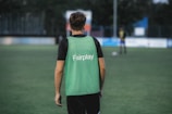 man in green and black adidas tank top and black pants standing on green grass field